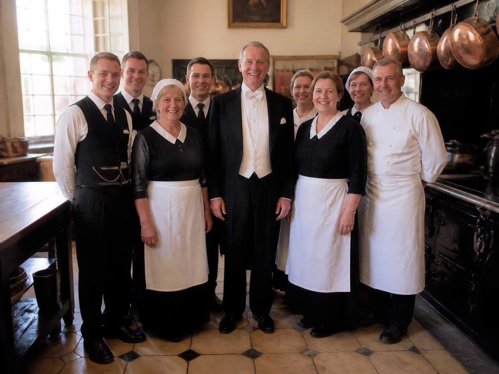 Household staff of an English country manor gathered in the kitchen with the head butler